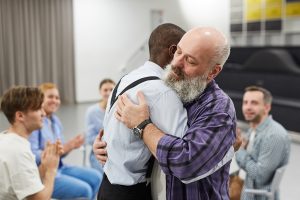 Recovery society session, 2 men hugging